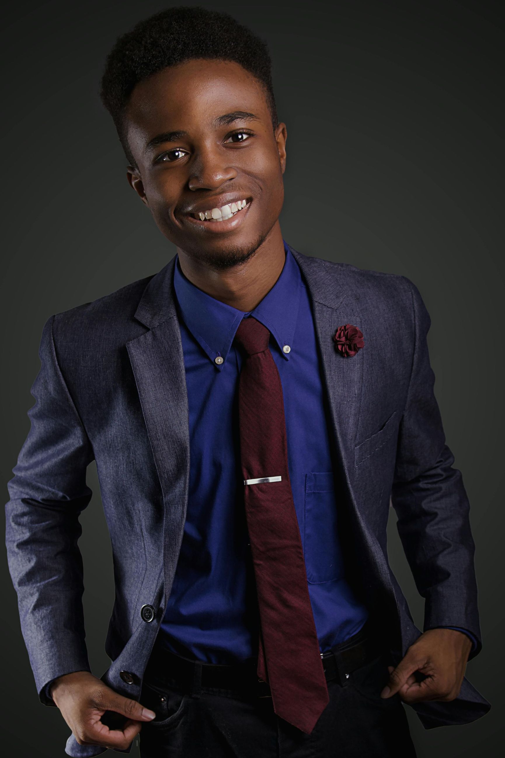 A young man in a suit and tie is smiling.