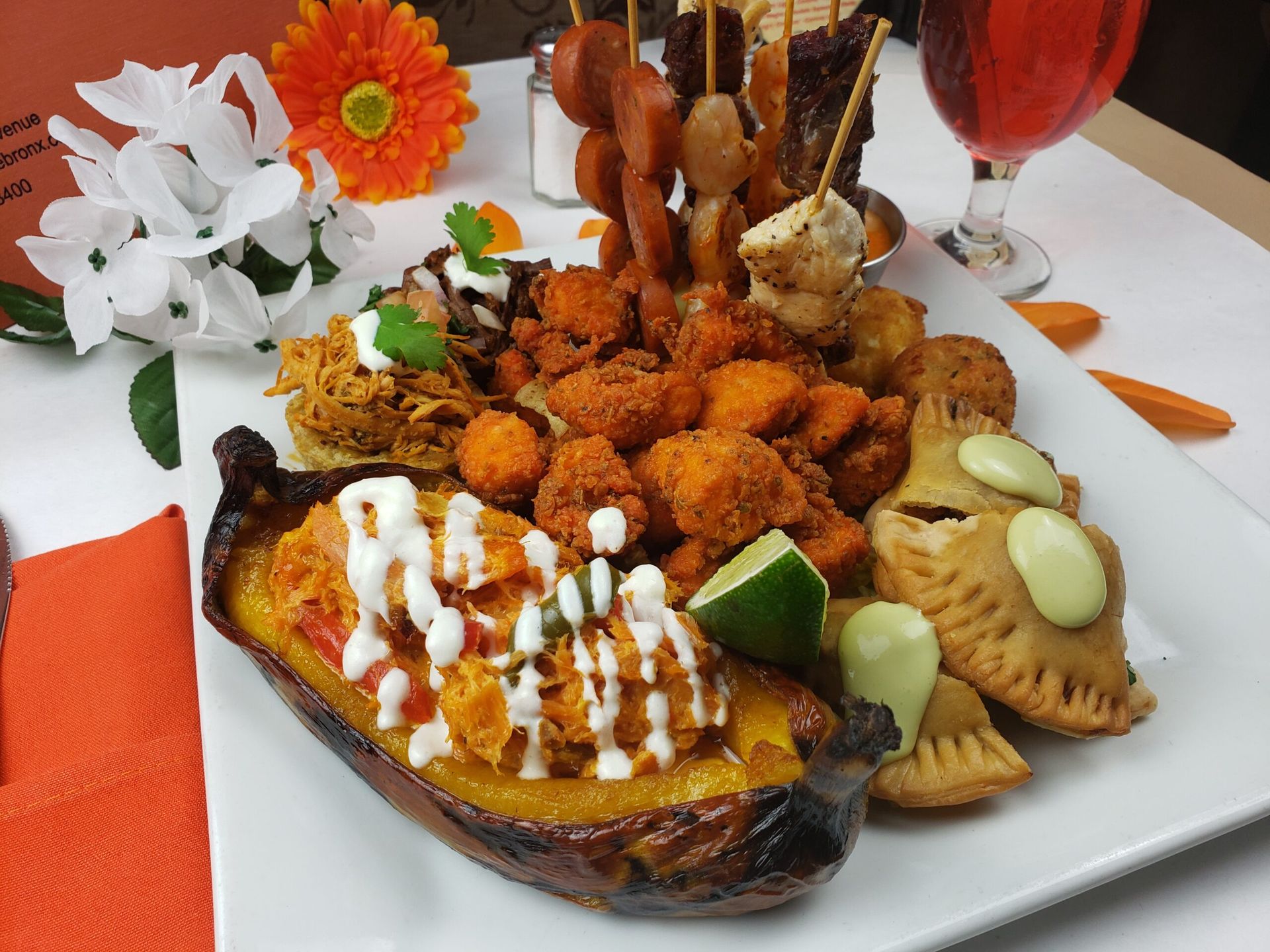 A platter of various fried foods and appetizers, including a plantain boat, on a white table.