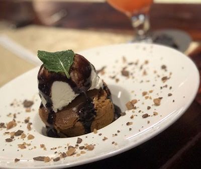 Chocolate lava cake with ice cream, chocolate sauce, and mint on a white plate.