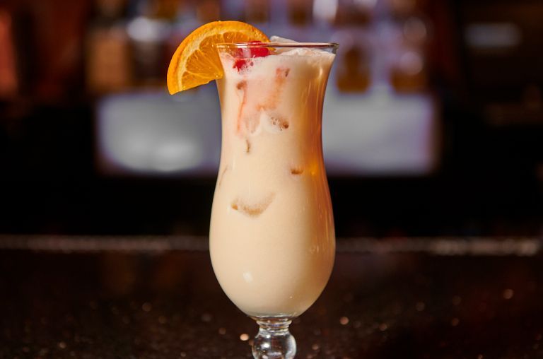 Creamy tropical cocktail in a glass, orange slice garnish.