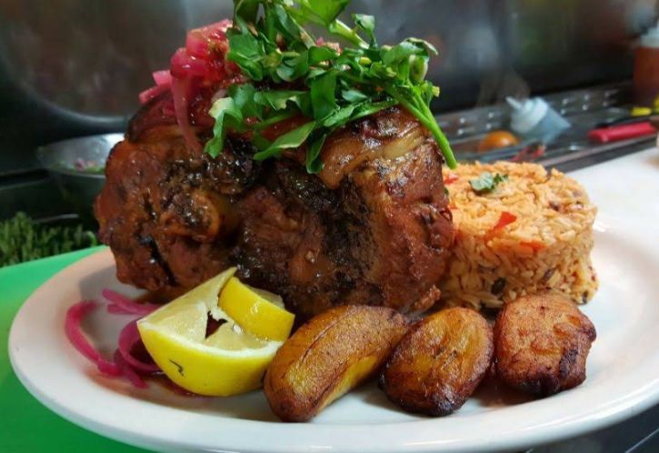 Plate of cooked meat, rice, plantains, lemon, and cilantro.