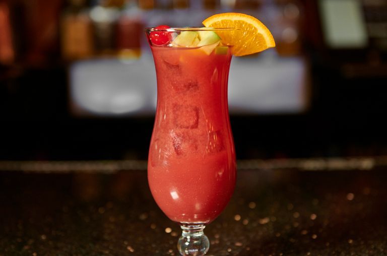 Hurricane cocktail in a glass with fruit garnish.