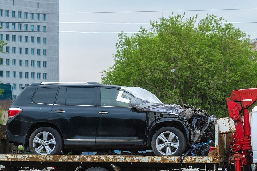 A black suv is being towed by a tow truck.