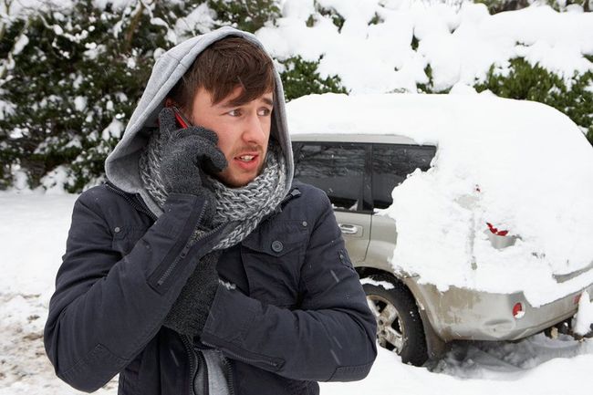 A man is standing in the snow talking on a cell phone.