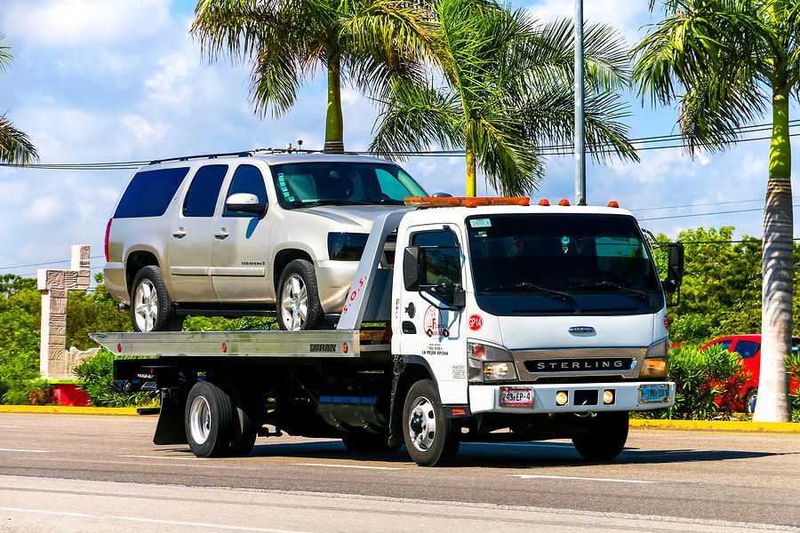 A tow truck is carrying a suv on the back of it.