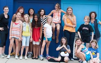 A group of young girls are posing for a picture in front of a blue wall.