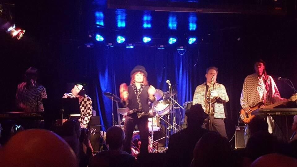 A group of people are playing instruments on a stage in a dark room.