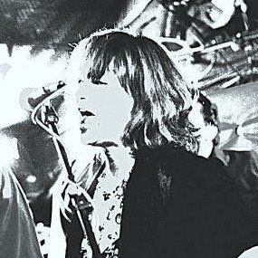 A black and white photo of a woman singing into a microphone.