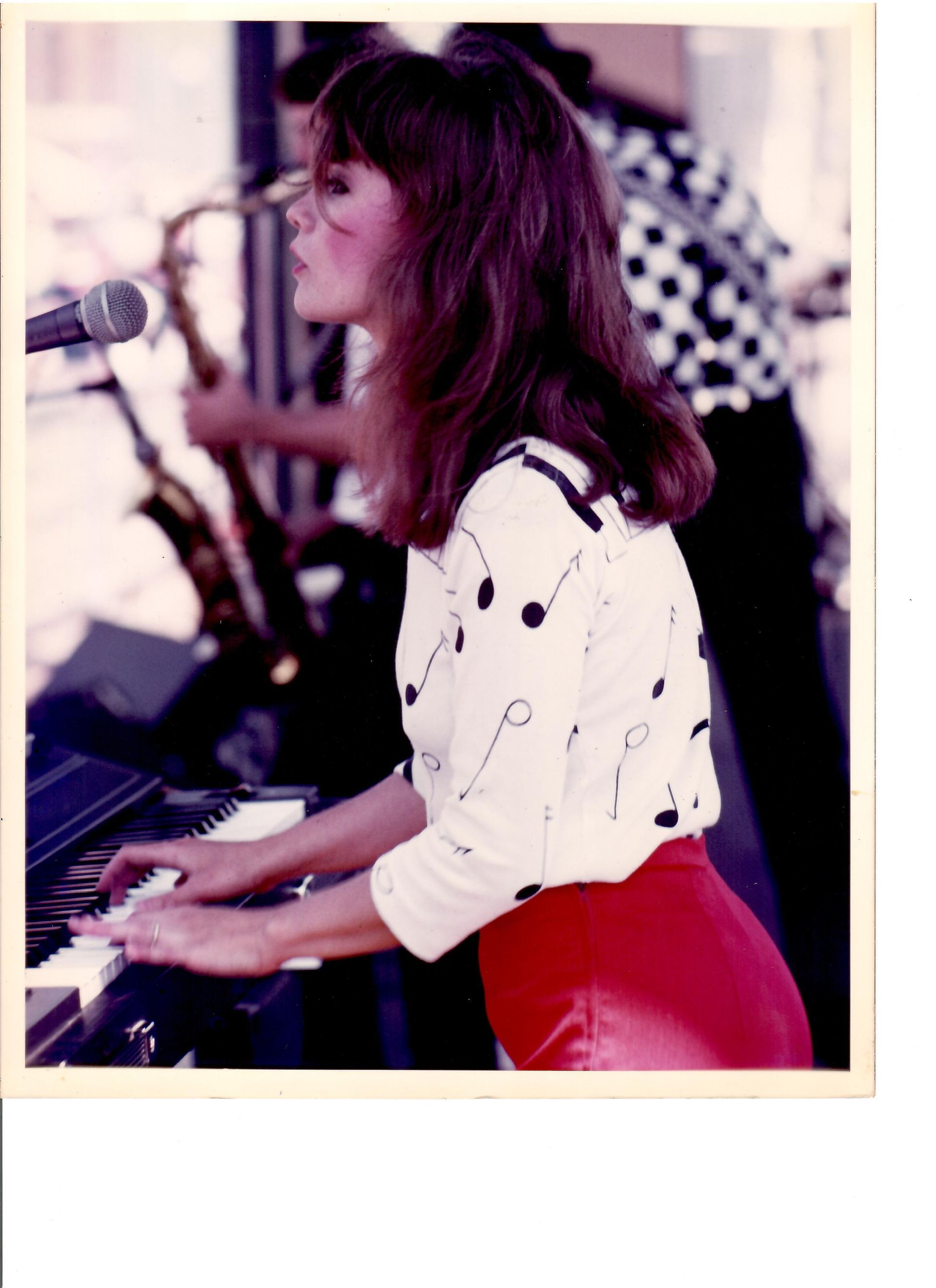 A woman is playing a piano and singing into a microphone