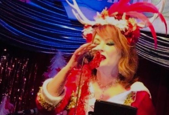 A woman in a santa costume is singing into a microphone