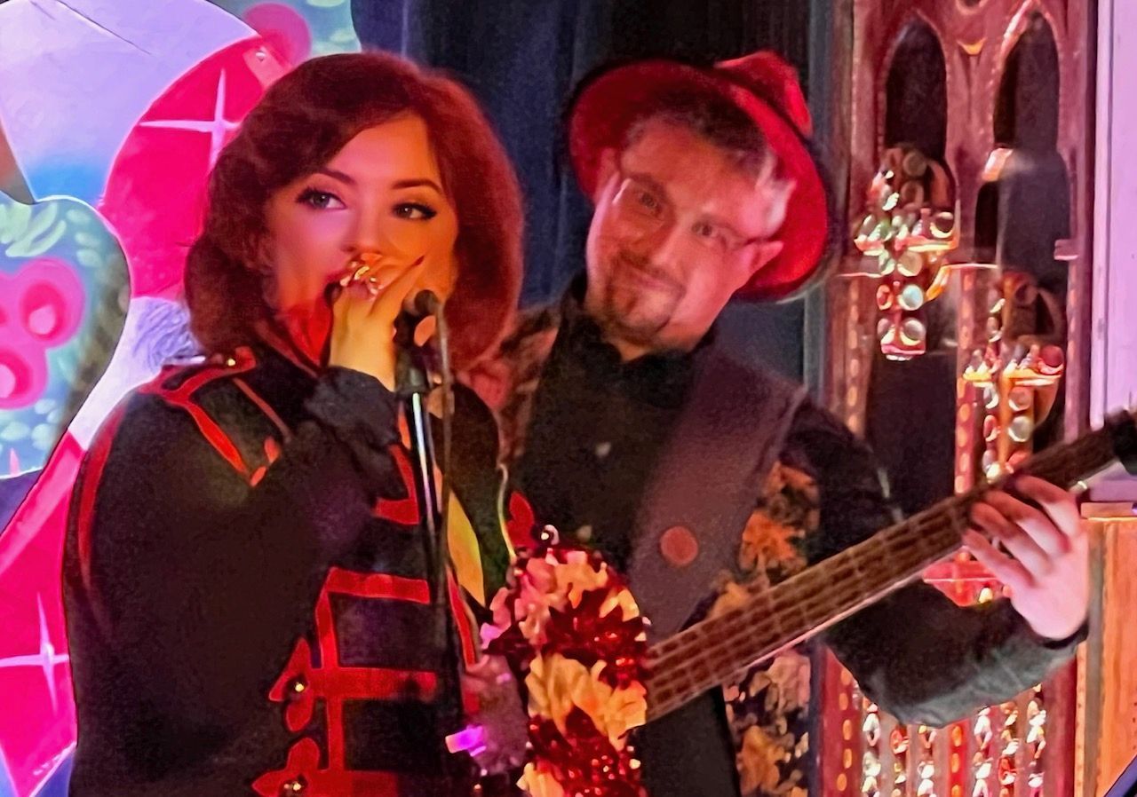 A man is playing a guitar and a woman is singing into a microphone.