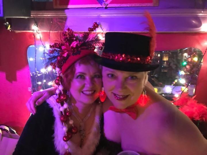 Two women are posing for a picture and one is wearing a top hat.