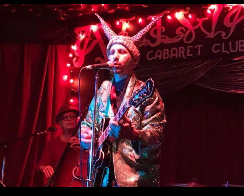 A man singing into a microphone in front of a sign that says cabaret club