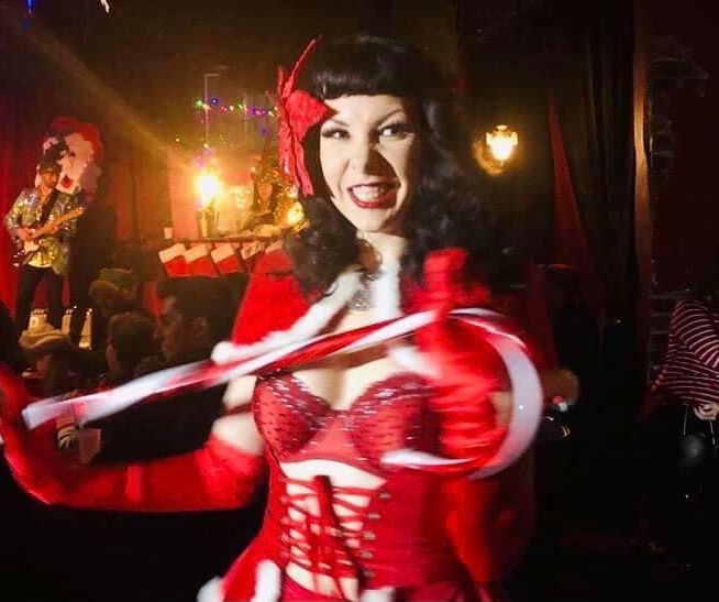 A woman in a red dress is holding a candy cane