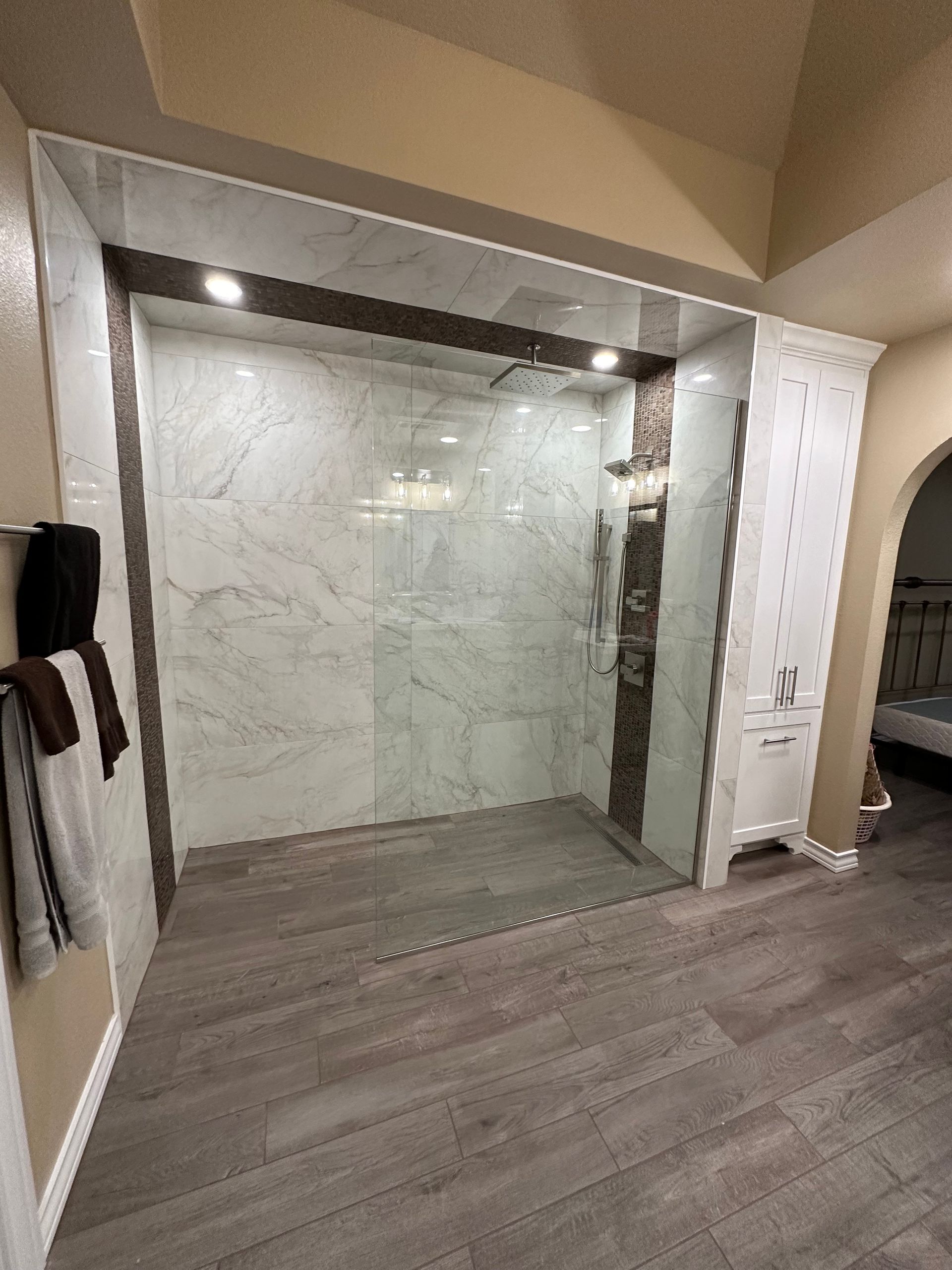 Remodeled shower space with large format tile and a decorative mosaic band of tile. 