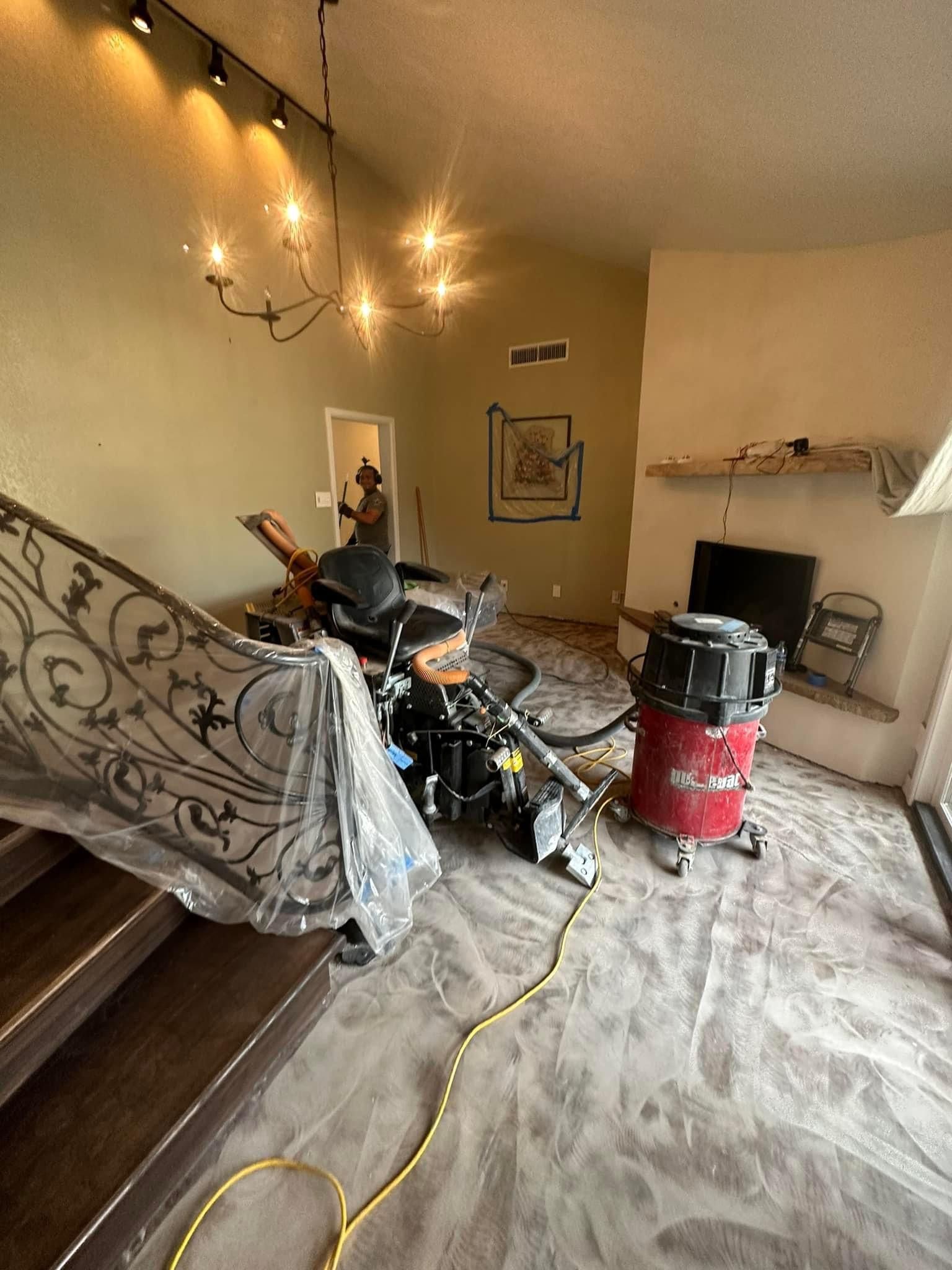 A picture of a hepa vauum, ride on floor scraper and structures covered with plastic to maximize dust control during the tile removal process. 