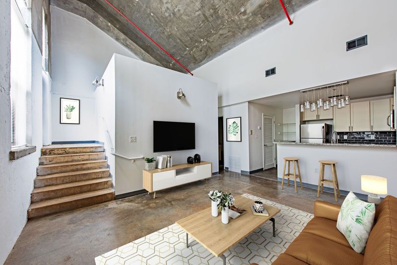 A living room with a couch , table and chairs and a kitchen in the background.