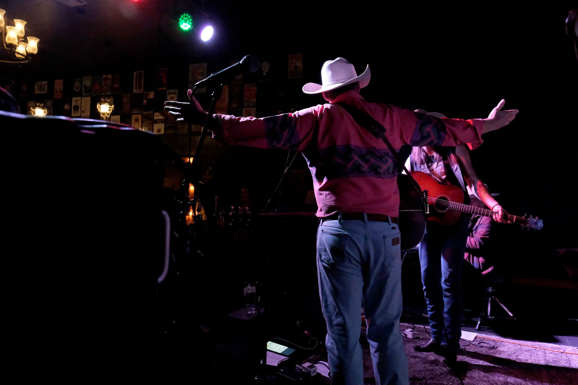 Man in cowboy hat with arms outstretched onstage with a guitarist.