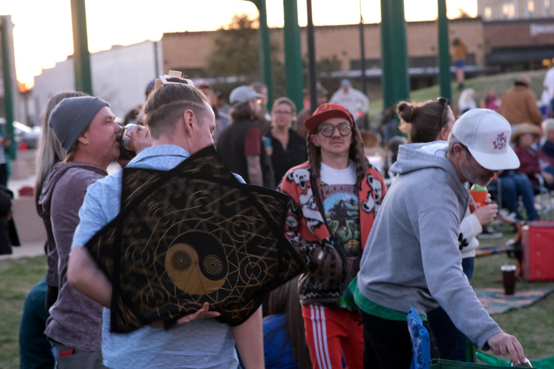 People at an outdoor gathering, one holding a star-shaped decoration with a yin-yang symbol.