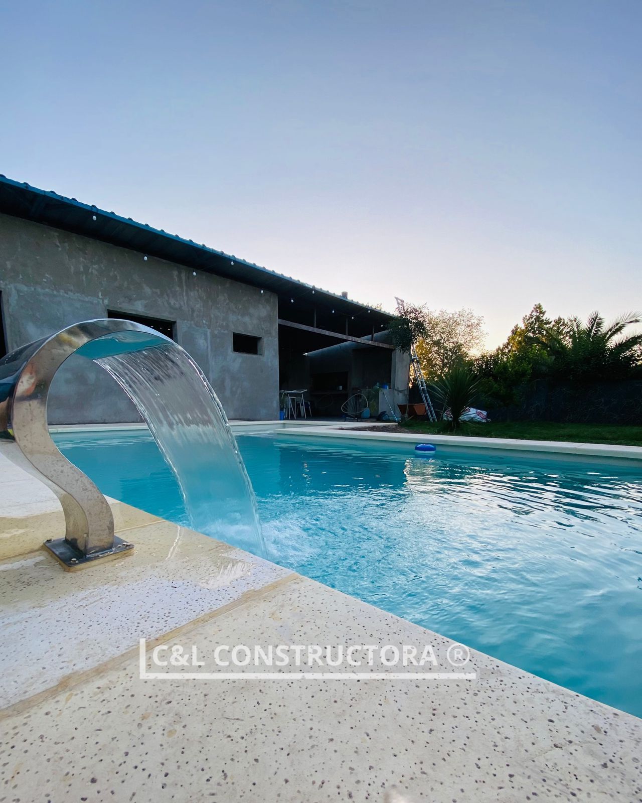 Piscina con jacuzzi y tumbonas en un patio trasero con una casa al fondo.