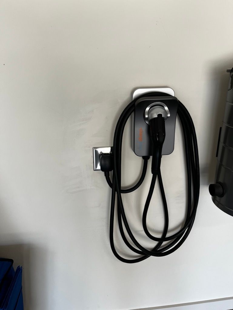 A black cord is hanging from a hook on a wall.