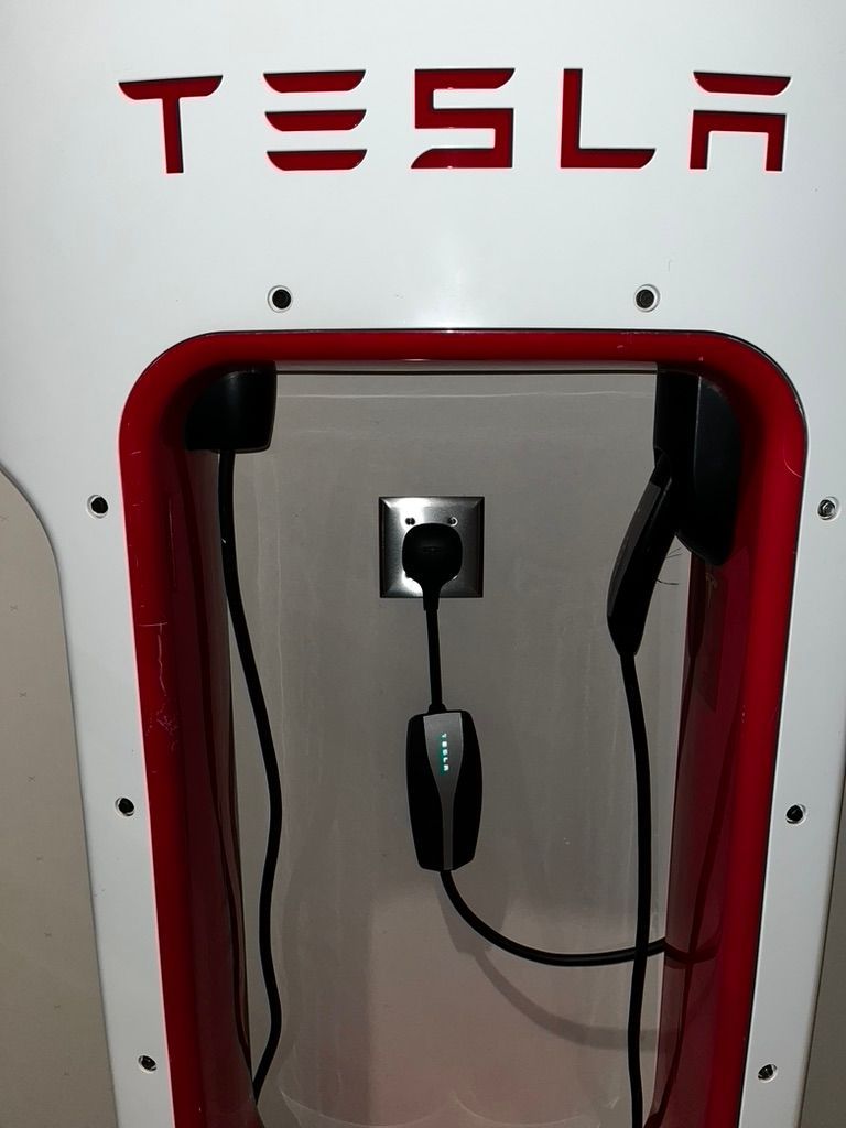 A tesla charging station with a cord plugged into it