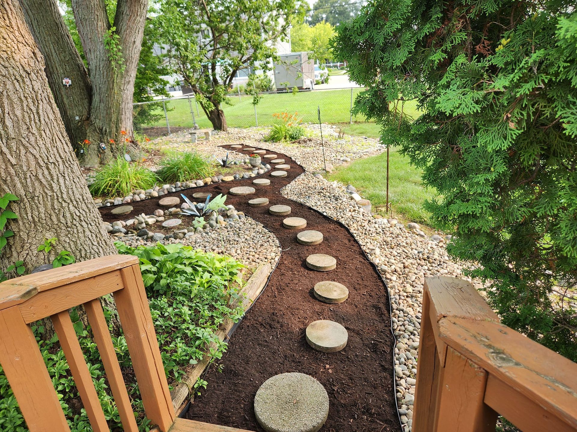 Stone path curves through landscaped yard, with mulch and rocks alongside.