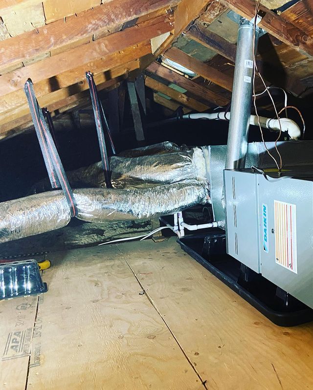 An air conditioner is sitting in the attic of a house.