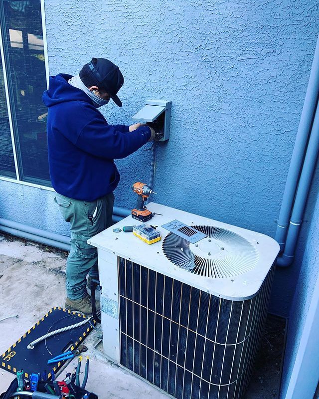 A man is working on an air conditioner outside of a building.