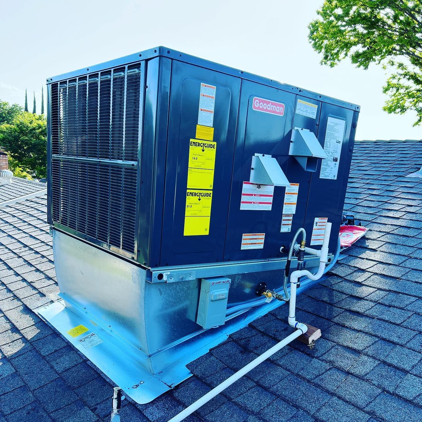 A black air conditioner is sitting on top of a roof.