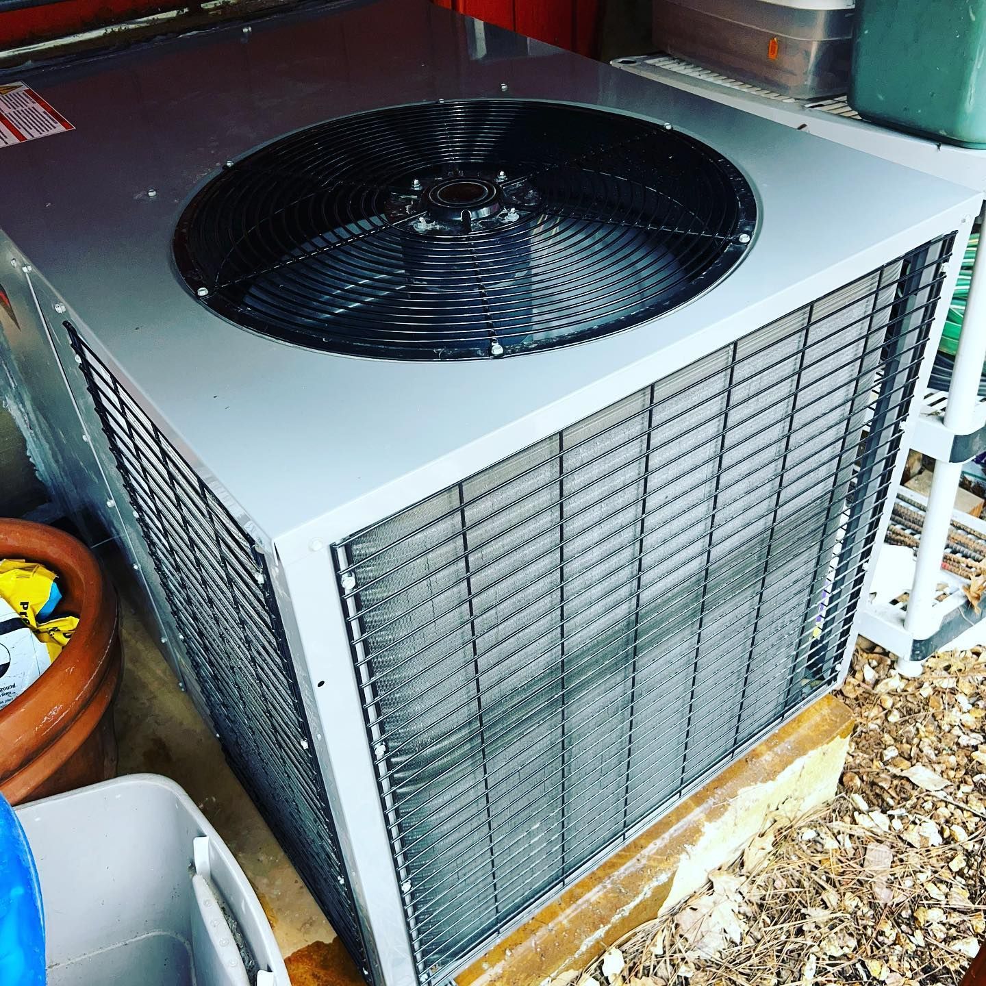 A large air conditioner is sitting on the ground next to a potted plant.