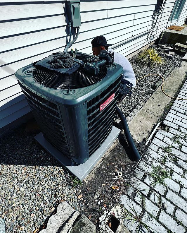 A man is working on an air conditioner outside of a house.