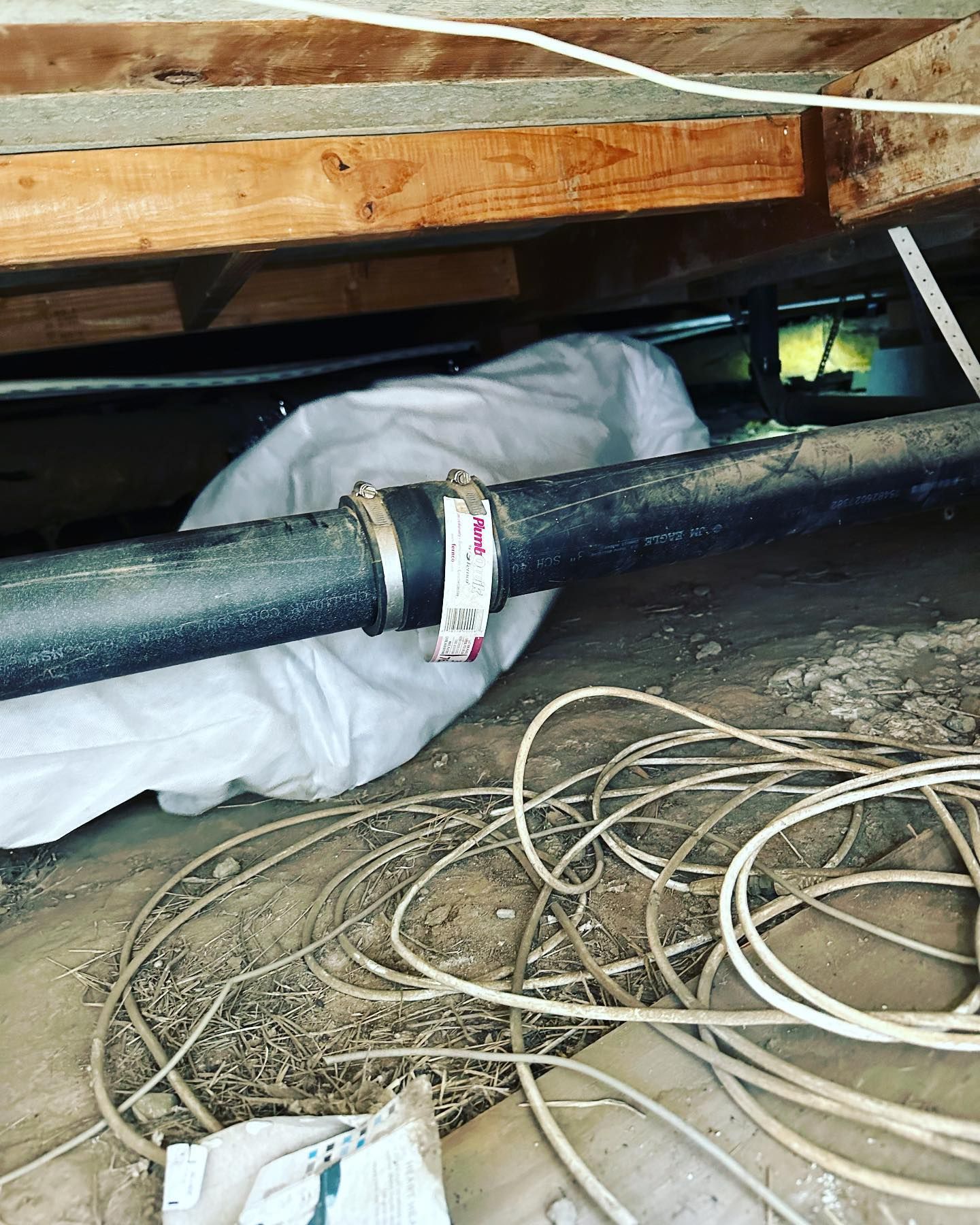 A pipe is laying on the ground under a house.