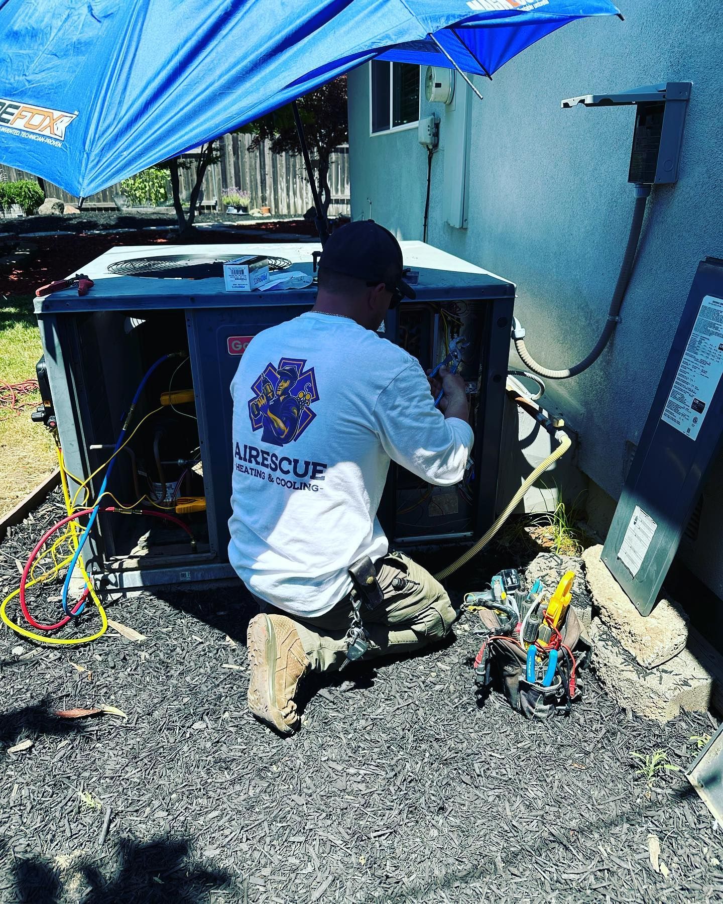 A man is kneeling down working on an air conditioner.