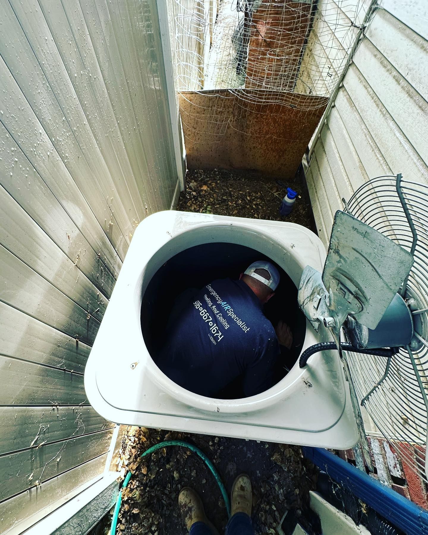 A man in a blue shirt is working on an air conditioner.