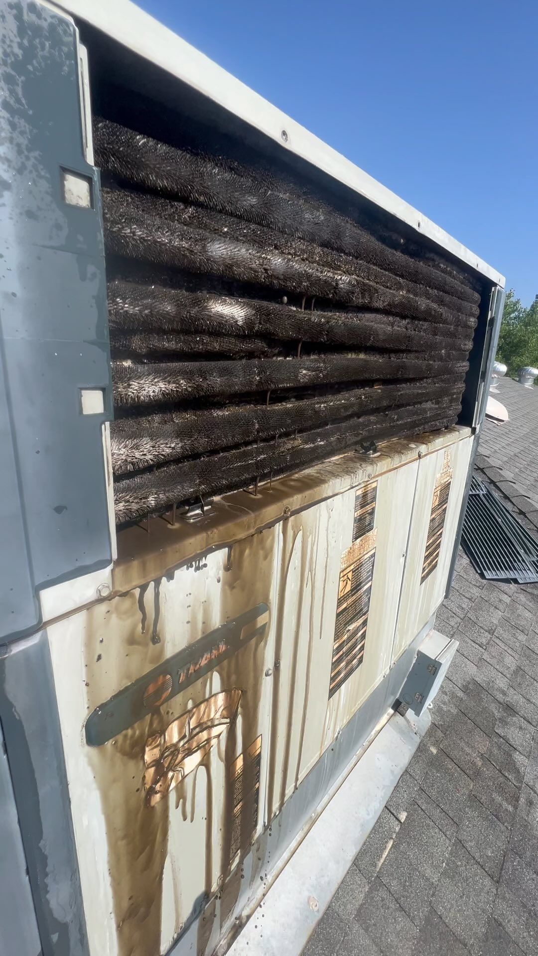 A close up of a dirty air conditioner on a roof.