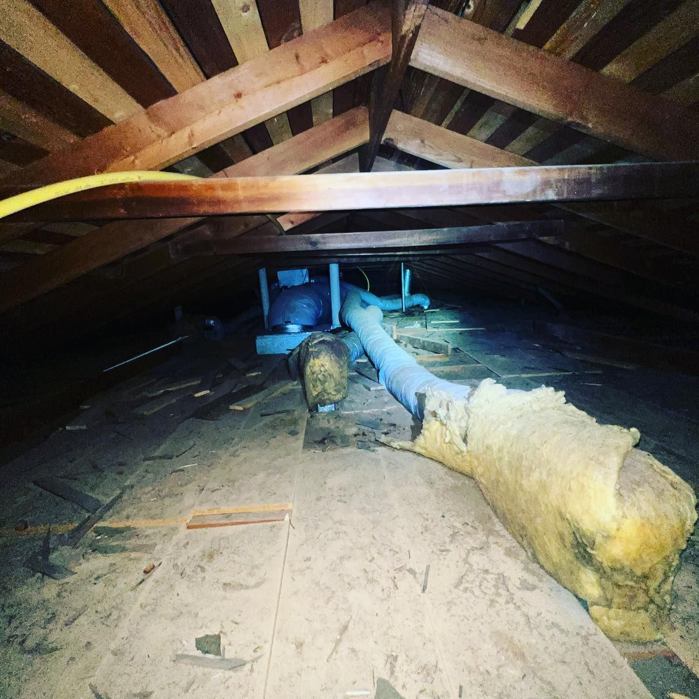 An attic with a lot of wooden beams and pipes.