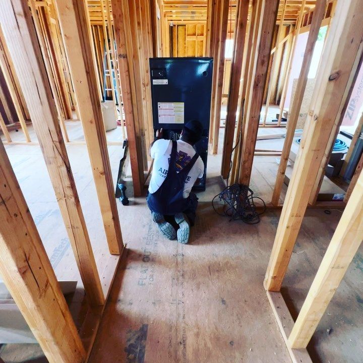 A man in overalls is kneeling down in a building under construction
