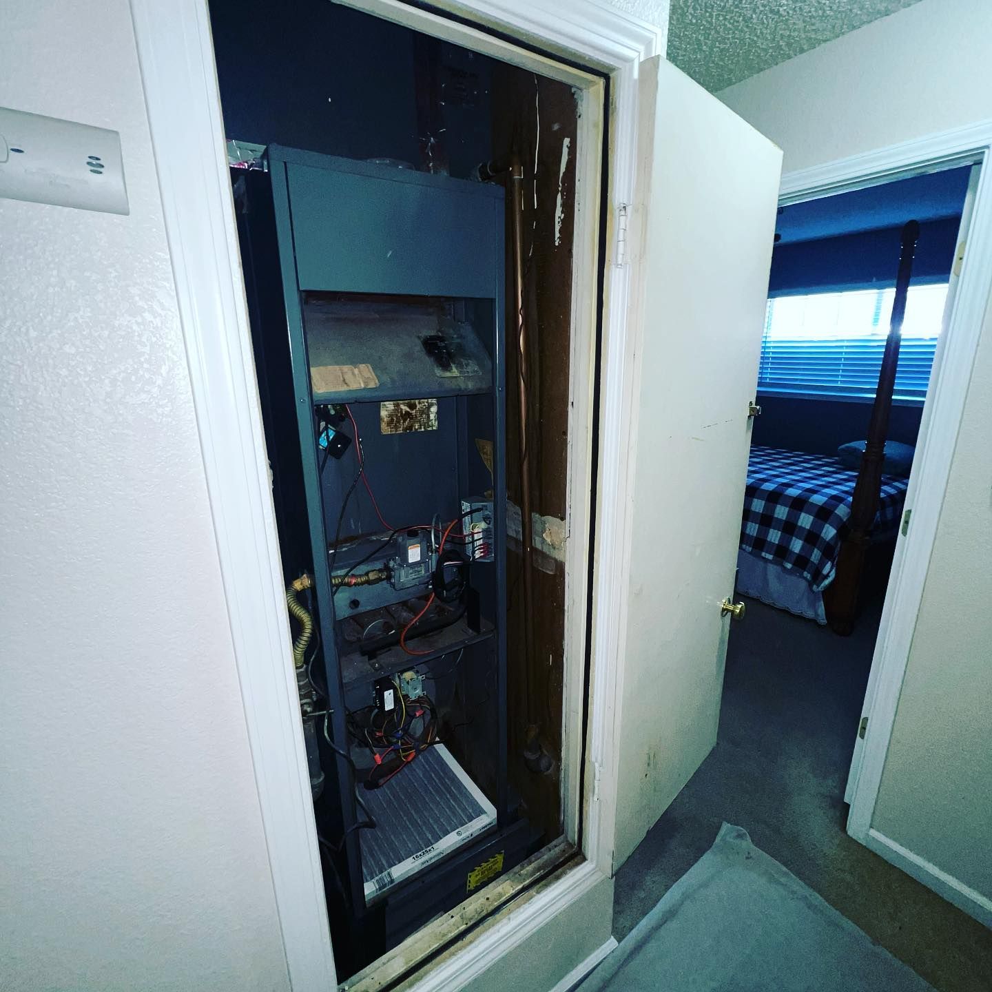 A closet with a heater inside of it and a bedroom in the background