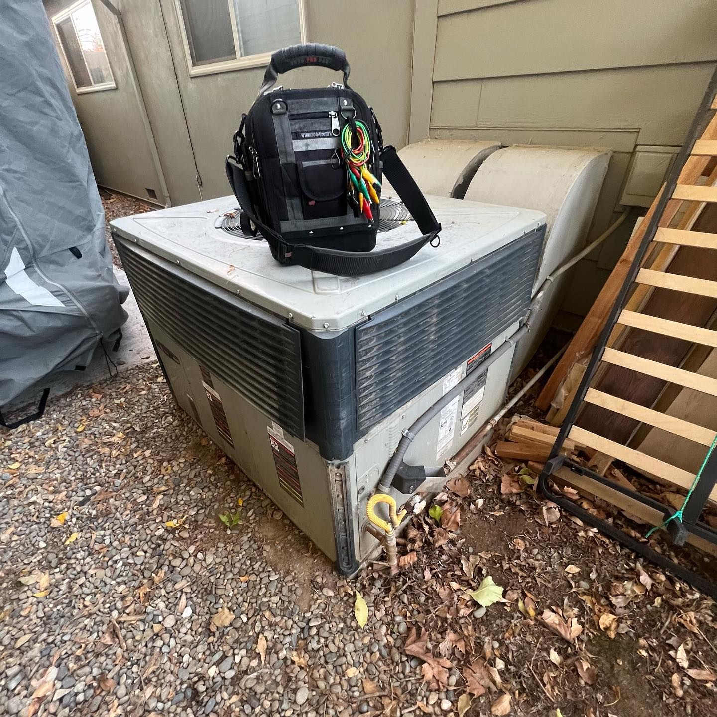 A bag is sitting on top of an air conditioner.