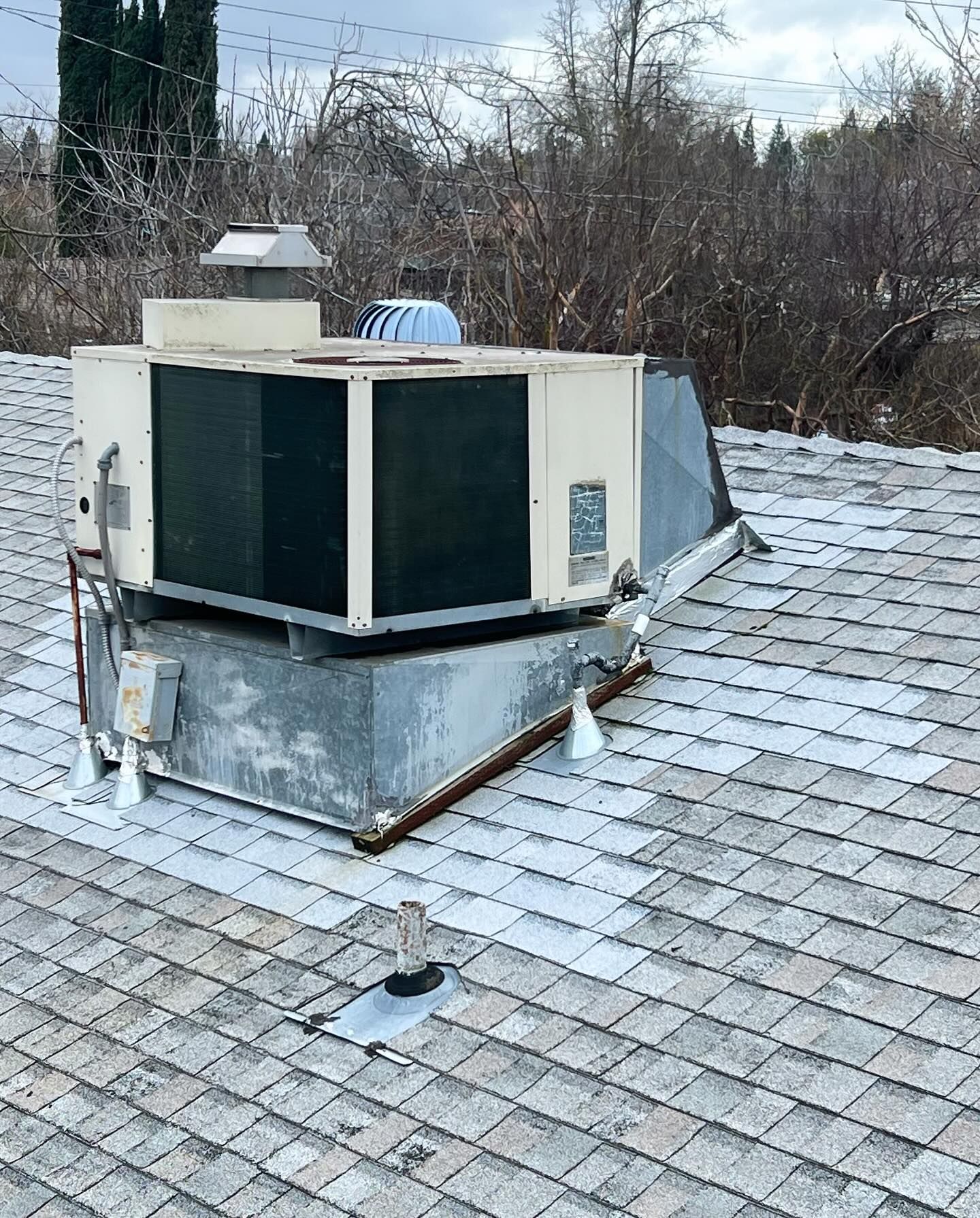 A large air conditioner is sitting on top of a roof.
