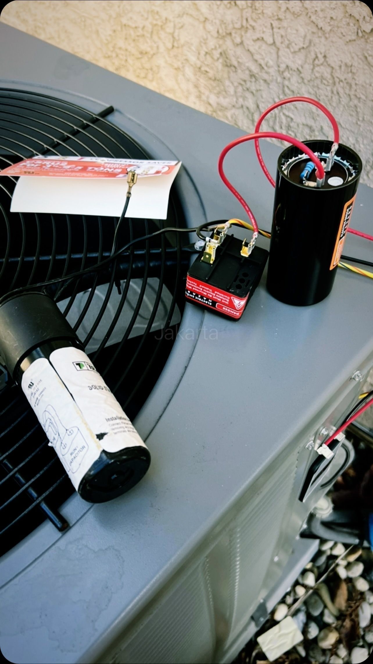 Two capacitors are sitting on top of an air conditioner