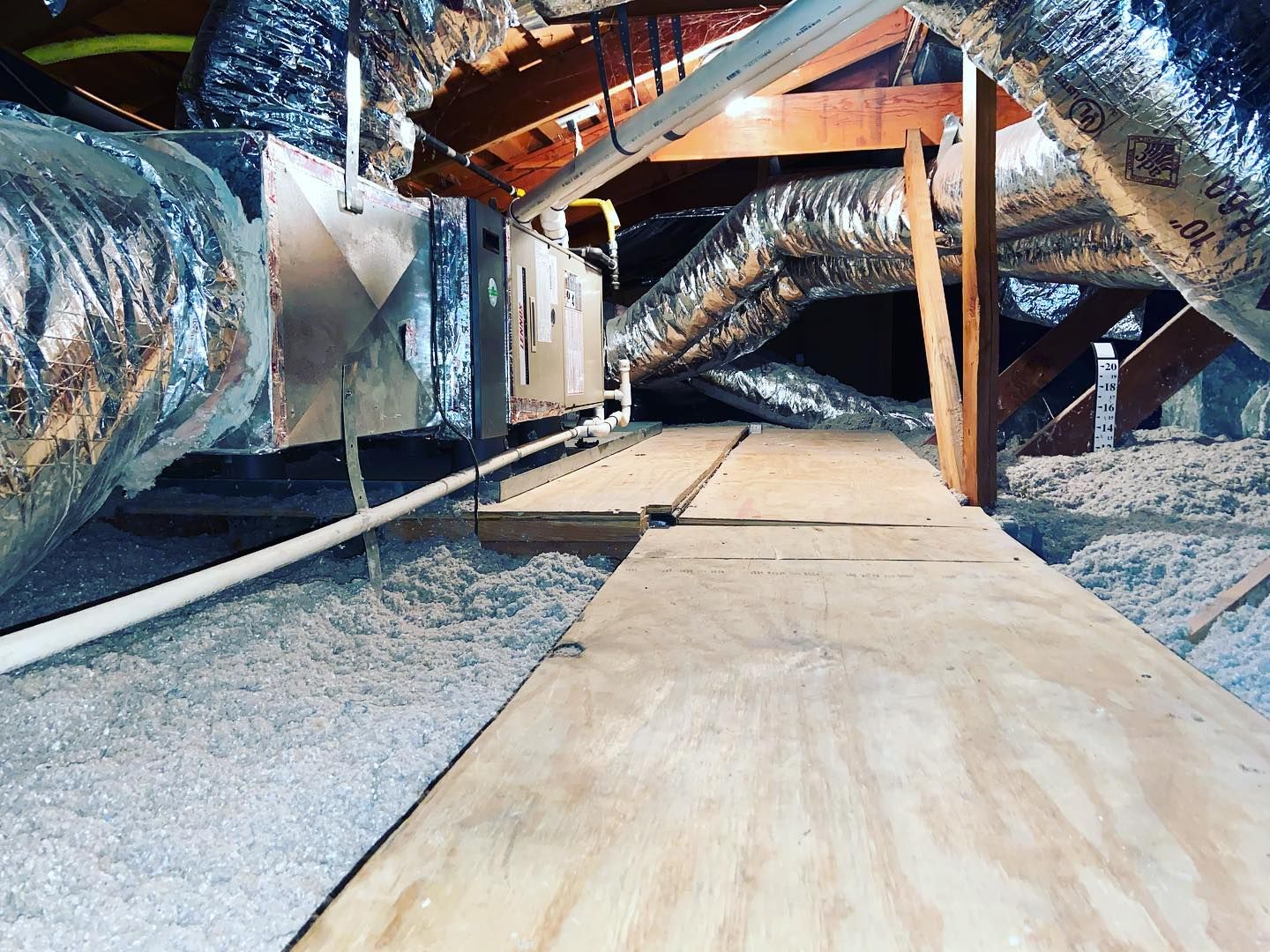 An attic with a lot of ducts and a wooden floor