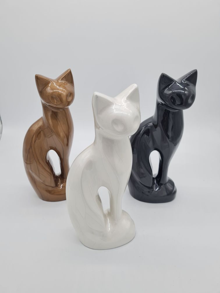 Three Ceramic Cat Figurines: Bronze, White, and Black, Posed on a White Surface — Furever Pet Cremations in Rockhampton, QLD