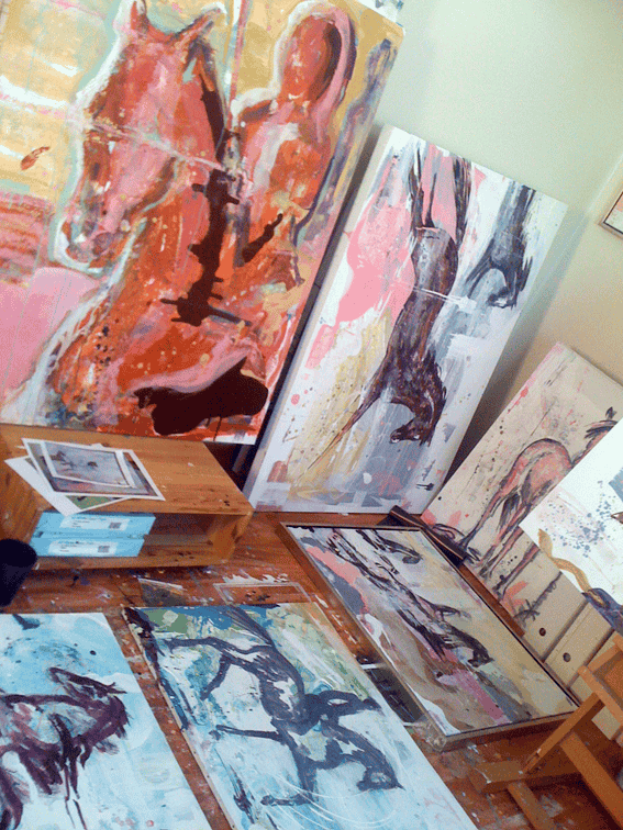 En haug med malerier sitter på et bord i et rom