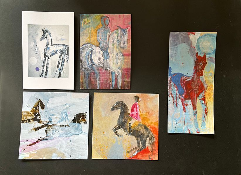 Fire malerier av hester og ryttere henger på en svart vegg.