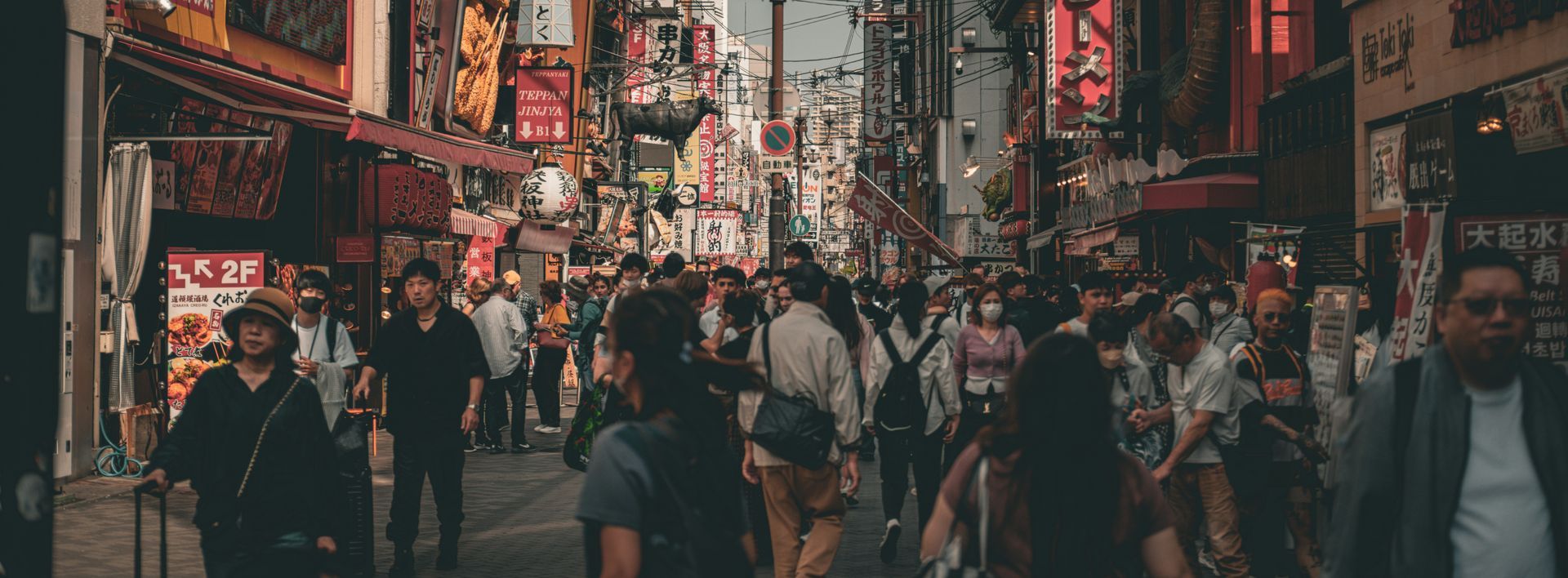 Einheimische essen Street Food in Osaka an Takoyaki-Ständen und offenen Theken im Viertel Dotonbori.