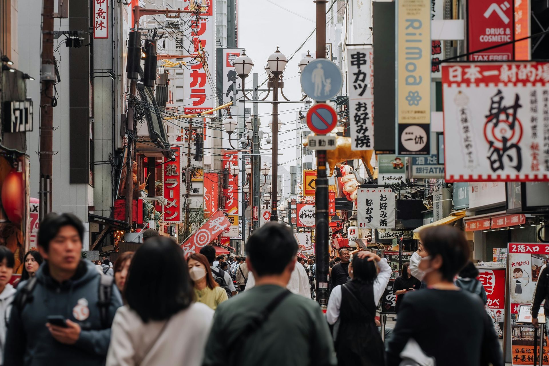 Lokaler Guide serviert Takoyaki unter den Neonlichtern von Dotonbori während einer Food Tour in Osak