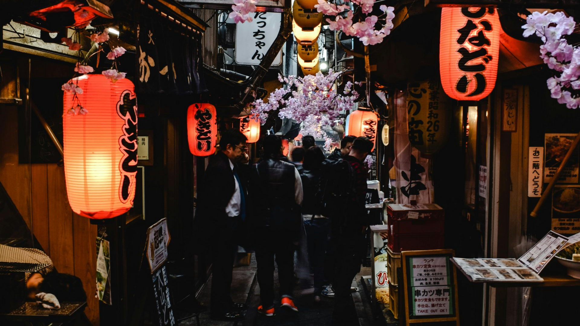 Reisende schlendern durch Laternen-gesäumte Essensstände in Ueno, Tokio