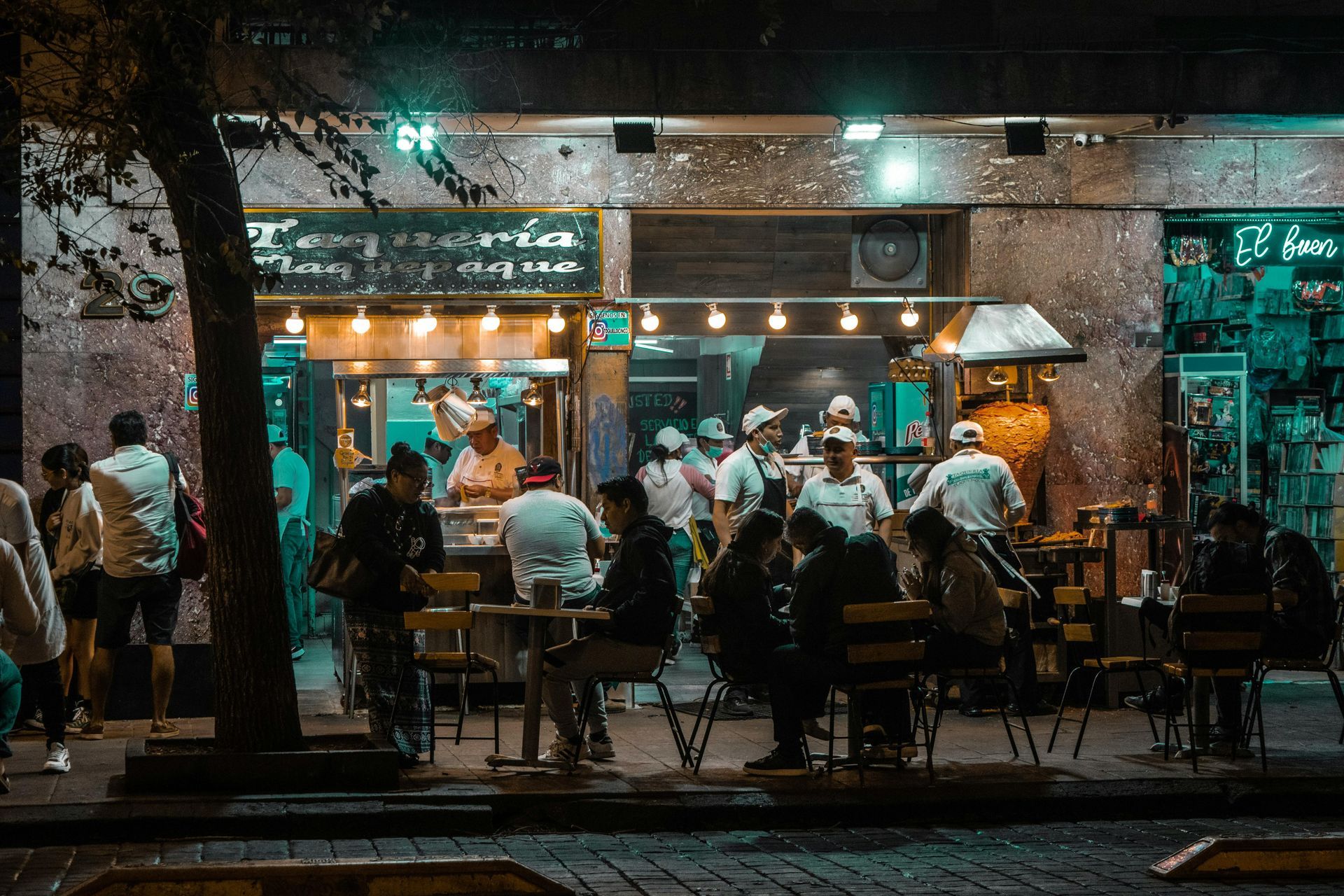 Reisende teilen Tacos und Birria an einem Straßenstand in La Condesa, Mexiko-Stadt.